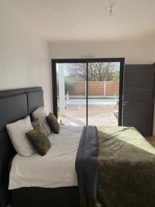 ein Schlafzimmer mit einem Bett und einer Glasschiebetür in der Unterkunft Villa Luxe Exclusive avec Piscine Privée in Gujan-Mestras