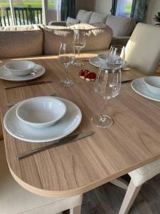 a wooden table with plates and wine glasses on it at The Lookout-Ribble Valley. Amazing home Gisburn in Gisburn