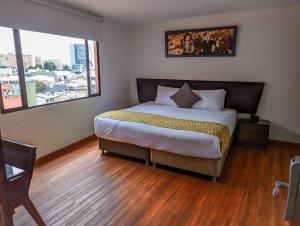 a bedroom with a large bed and a large window at Hotel Charlotte Suite 26 in Bogotá