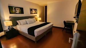a hotel room with a large bed and a desk at Hotel Charlotte Suite 26 in Bogotá