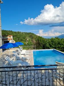 a swimming pool with chairs and a blue umbrella at Villa Eva Šestanovac, Katuni, Omiš in Šestanovac