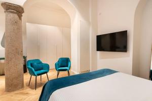 a bedroom with two blue chairs and a tv at LA SCALA SUITE-Luxury Apartment in Milan