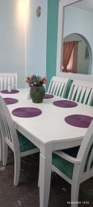 una mesa blanca con sillas y un jarrón con flores. en Marilidia House, en Kastéllion