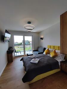 ein Schlafzimmer mit einem Bett, einem Sofa und einem Fenster in der Unterkunft WIŚLANY PORT WILLA in Krynica Morska