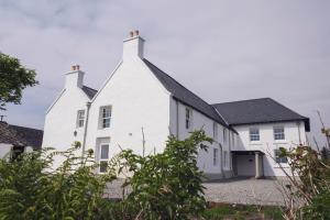 una casa blanca con techo negro en Ullinish House en Ullinish