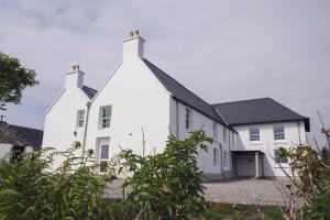 una casa blanca con techo negro en Ullinish House, en Ullinish