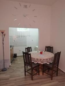 a dining room table with chairs and a clock on the wall at T.I.M. in Bela Crkva