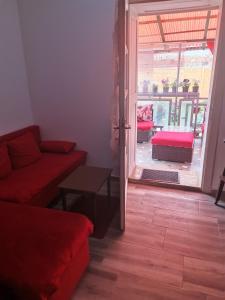 a living room with a red couch and an open door at T.I.M. in Bela Crkva