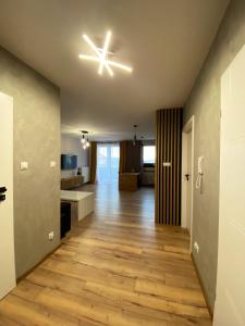 a living room with a ceiling light and wooden floors at Apartament Sanok nad stawami in Sanok