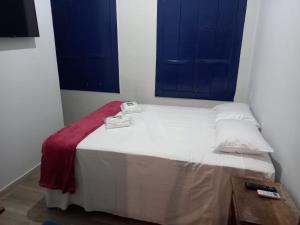 Cama pequeña en habitación con ventanas azules en Pousada Usina Paraíso en Astolfo Dutra