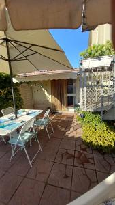een patio met een tafel en stoelen en een parasol bij Domus Claudio Garden - Monolocale con giardino privato in Fiumicino