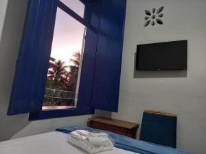 1 dormitorio con ventana azul, 1 cama y TV en Pousada Usina Paraíso en Astolfo Dutra