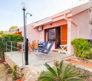 una casa con patio dotato di sedie e lampada di Villa Bellavista IS MOLAS PULA, CAGLIARI a Santa Margherita di Pula