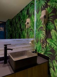 uma casa de banho com um lavatório e um mural de plantas em Insula Living Juanambu em Cali