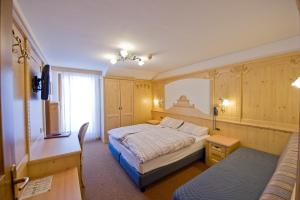 a bedroom with a bed and a desk and a couch at Hotel San Marco in Passo San Pellegrino +43 photos