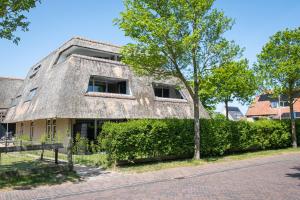 een oud huis met een rieten dak en een boom bij Waddenresidentie Ameland in Buren