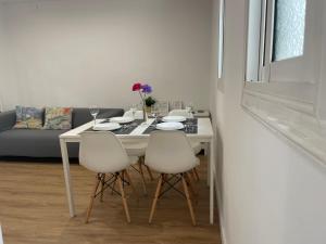 mesa de comedor blanca con 4 sillas blancas en Apartamento Kemacu, en Barcelona
