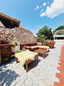 patio z kanapą i stołami oraz kamienną ścianą w obiekcie Apartment Melani w mieście Vir