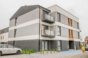 een witte auto geparkeerd voor een gebouw bij Apartamenty Warzywna in Leszno