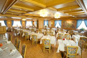 una sala da pranzo con tavoli e sedie bianchi di Hotel San Marco a Passo San Pellegrino