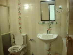 y baño con aseo, lavabo y espejo. en Lazar Residency Homestay, en Kochi
