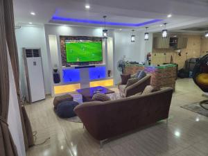a living room with a tv and a couch and chairs at Exquisite and Cozy 3-bedroom Apt with hot-tub and WiFi in Agege