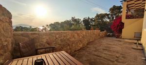 a wooden bench sitting next to a stone wall at Buena Vista in Aegenitissa