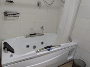 a white bath tub in a white tiled bathroom at Exquisite and Cozy 3-bedroom Apt with hot-tub and WiFi in Agege