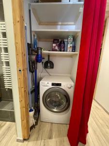 a washing machine in a laundry room with a red curtain at Appartement "Le Sporting" à 5 min des pistes in La Salle Les Alpes
