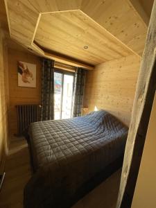 a bedroom with a bed in a wooden room at Appartement "Le Sporting" à 5 min des pistes in La Salle Les Alpes