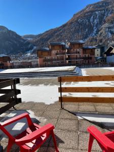 two red chairs and a bench on a roof at Appartement "Le Sporting" à 5 min des pistes in La Salle Les Alpes