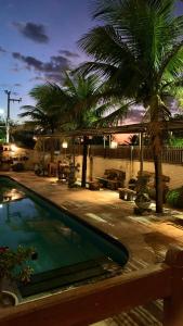 a swimming pool with palm trees in a yard at Pousada Borboleta in Canoa Quebrada