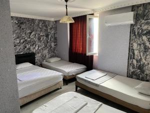 a room with three beds and a window and avertisement at SİES OTEL in Antalya
