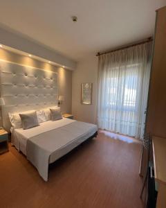 a bedroom with a large bed and a large window at Hotel Ardea in Riccione
