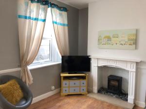 a living room with a fireplace and a television at Hilltop Cottage in Renishaw