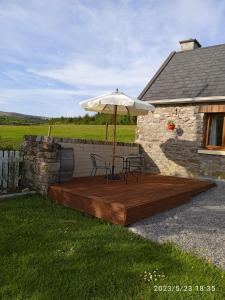 a wooden deck with an umbrella and two chairs on it at Nire Valley Cottage 