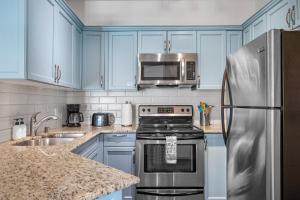 a kitchen with blue cabinets and a stainless steel refrigerator at Newly renovated Blue Sky - Family Fun - 2 Bed -2 Bath in Canmore