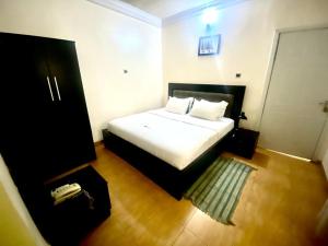 a bedroom with a white bed and a phone at Apartment A- 2 Bedroom Apartment) Hillside Gardens in Lagos