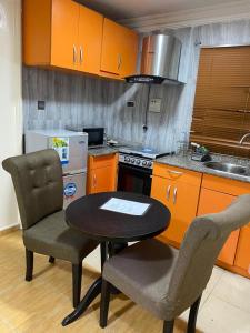 a kitchen with orange cabinets and a table and chairs at Apartment A- 2 Bedroom Apartment) Hillside Gardens in Lagos