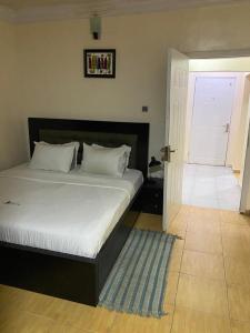 a bedroom with a bed and a door with a rug at Apartment A- 2 Bedroom Apartment) Hillside Gardens in Lagos