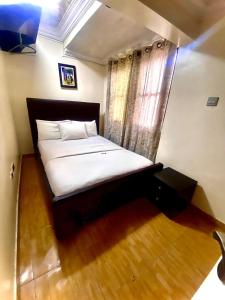 a bedroom with a large bed with white sheets and a window at Apartment A- 2 Bedroom Apartment) Hillside Gardens in Lagos