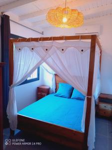 a bedroom with a canopy bed with blue pillows at Beach House à Terre de Haut in Terre-de-Haut