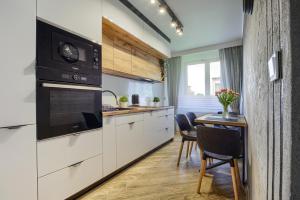 a kitchen with white cabinets and a table with chairs at Apart Dwudziestolecie in Wadowice