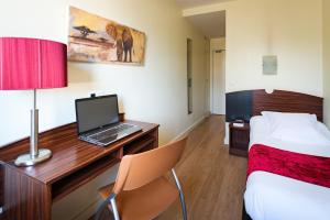 a hotel room with a bed and a desk with a laptop at Hôtel Icare in Toulouse