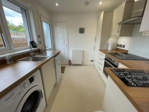 a kitchen with a washing machine and a sink at 'Edgewood' - detached bungalow in Inverness