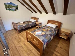 2 łóżka w pokoju z drewnianą podłogą w obiekcie Apartman Mediteran w Szybeniku
