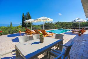 a patio with a table and chairs and a pool at Villa ChrisDina in Nýmfai
