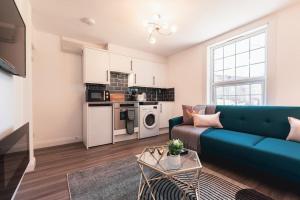a living room with a blue couch and a kitchen at Barite - 1 Bedroom Flat in Reading