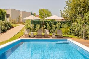 a swimming pool with two chairs and umbrellas next to at BFRESH Hotel - Padel, Pool & Fitness - Adults Only in Porto