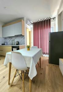 Il comprend une cuisine et une salle à manger avec une table et des chaises blanches. dans l'établissement Avalona Apartment 1, à Vlorë
